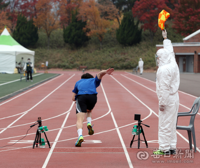 6일 계명대학교 성서캠퍼스에서 열린 2021학년도 수시모집 체육대학 실기고사 100m 달리기에서 방호복을 착용한 감독관이 수험생에게 출발 신호를 보내고 있다. 학교측은 수험생이 마스크를 벗고 달리기 때문에 코로나19 예방을 위해 감독관과 관리요원들에게 보호장비를 착용하도록 했다. 성일권 기자 sungig@imaeil.com