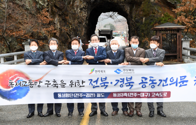 19일 전북 무주군 나제통문에서 동서교통망 구축을 위한 전북·경북 공동건의문을 채택하며 참석 단체장들이 손을 맞잡고 기념촬영을 하고 있다. 왼쪽부터 이병환 성주군수, 김충섭 김천시장, 이철우 경북도지사, 송하진 전북도지사, 황인홍 무주군수, 전춘성 진안군수, 최명규 전주부시장. 경북도 제공