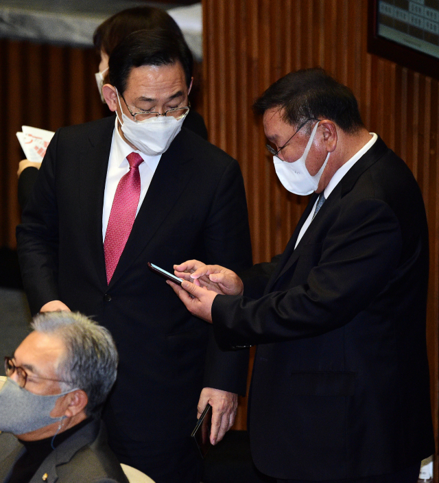 더불어민주당 김태년 원내대표(오른쪽)와 국민의힘 주호영 원내대표가 지난 19일 국회 본회의에서 휴대전화를 보며 대화하고 있다. 연합뉴스