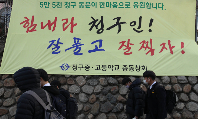 2021학년도 대학수학능력시험 앞두고 마지막 등교를 한 대구 청구고등학교 재학생들이 25일 오후 학교 담벼락에 걸린 수험생 응원 현수막 앞을 지나가고 있다. 김영진 기자 kyjmaeil@imaeil.com