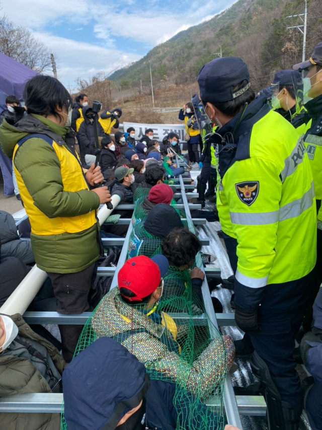 27일 사드 기지에 공사자재 차량 등을 반입하기 위해 경찰이 사드반대 측 해산에 나서자 철구조물에 몸을 묶은 이들이 극렬하게 저항하고 있다. 소성리종합상황실 제공