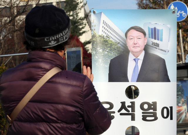 지난 26일 오전 서울 서초구 대검찰청 앞에서 한 시민이 윤석열 검찰총장의 모습이 나온 배너를 휴대전화 카메라로 찍고 있다. 연합뉴스