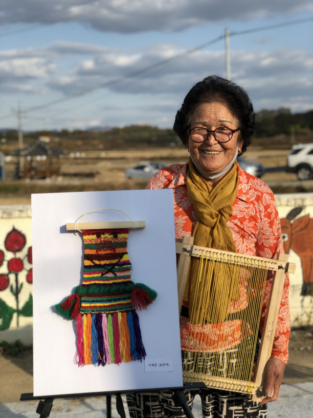 경북 의성군 단밀면 서제1리의 할매들이 서울 청담동에서 작품 전시회를 연 가운데 한 할매가 자신의 작품을 들고 기념 사진을 촬영하고 있다. 의성군 제공