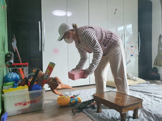 전재영(가명·30) 씨가 아들 김태환(가명·8) 군을 학교에 보낸 뒤 아이의 장난감을 주워 담으며 집정리를 하고 있다. 배주현 기자