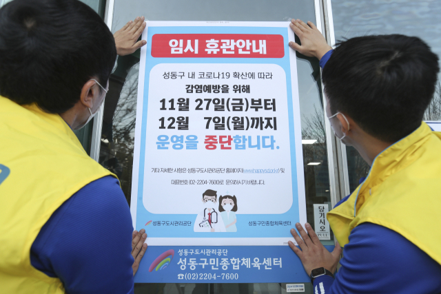 서울 성동구가 지역 내 공공시설에 사회적 거리두기 3단계에 준하는 방역 조치를 시행한다고 발표한 가운데 26일 성동구민종합체육센터 관계자들이 오는 27일부터 운영을 중단한다는 안내문을 출입문에 부착하고 있다. 성동구 제공.