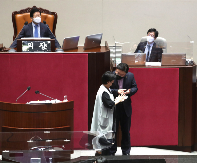 국민의힘 윤희숙 의원(왼쪽)이 12일 오전 국회 본회의에서 국가정보원법 전부개정 법률안에 대한 무제한 토론 도중 김성원 원내수석부대표와 대화하고 있다. 이날 본회의는 전날 필리버스터에 나선 한 의원이 코로나19 확진자와 접촉, 방역을 위해 윤 의원 순서가 끝난 뒤 정회됐다. 연합뉴스
