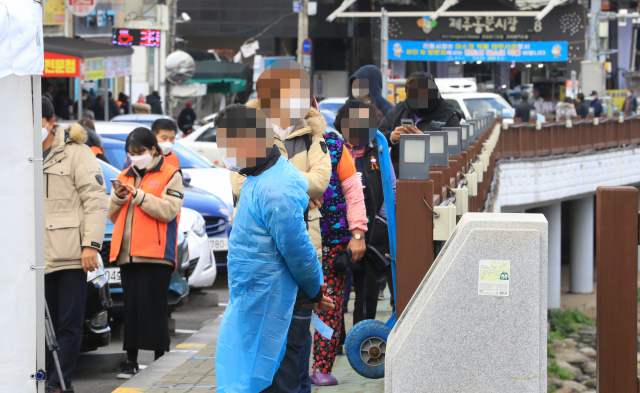20일 오후 제주시 동문시장 인근 주차장에 마련된 코로나19 임시 선별진료소를 찾은 시민들이 줄지어 검사 순서를 기다리고 있다. 연합뉴스