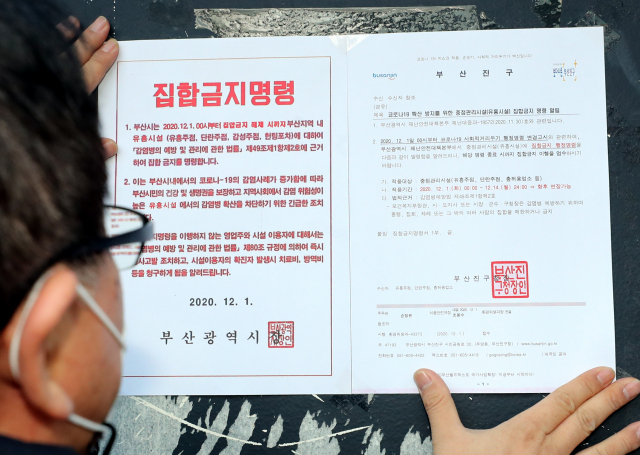 최근 확진자 급증으로 부산에서 사회적 거리두기가 2단계가 시작된 1일 오후 부산진구 직원들이 서면 일대 유흥시설에 집합 금지 행정명령문을 부착하고 있다. 연합뉴스