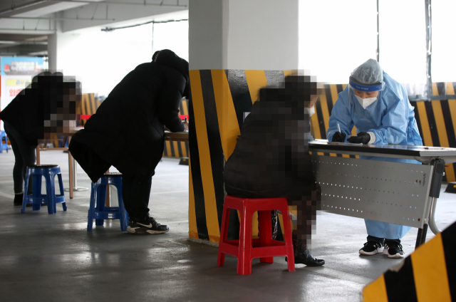 선별진료소에서 의료진이 신종 코로나바이러스(코로나19) 감염증 검사를 받기 위해 방문한 시민들의 문진표 작성을 돕고 있다. 연합뉴스