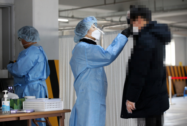22일 오후 광주 북구보건소 선별진료소에서 의료진이 신종 코로나바이러스(코로나19) 감염증 검사를 받기 위해 방문한 시민의 체온을 측정하고 있다. 연합뉴스