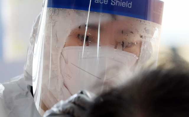 지난 23일 오전 광주 북구선별진료소에서 검체를 채취하는 보건소 의료진의 페이스쉴드에 습기가 서려있다. 연합뉴스