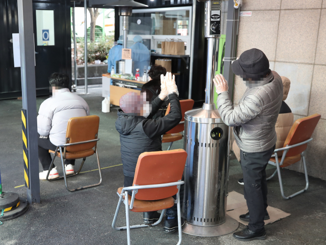 절기상 소한인 5일 오후 서울 동작구보건소에 마련된 임시 선별진료소를 찾은 시민들이 검체 검사 순서를 기다리며 난로에 손을 녹이고 있다. 연합뉴스