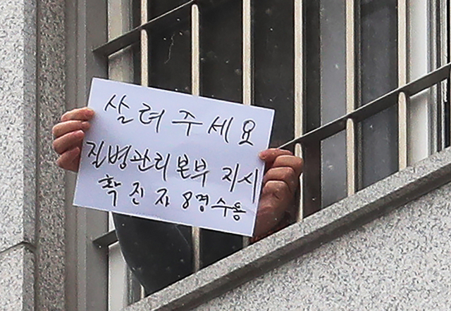 29일 오후 서울 송파구 동부구치소에서 한 수용자가 확진자 과밀수용 등 불만 사항을 직접 적어 취재진을 향해 들어 보이고 있다. 어제 동부구치소에서 233명의 확진자가 추가돼 지금까지 이곳에서만 총 757명이 감염됐다. 연합뉴스