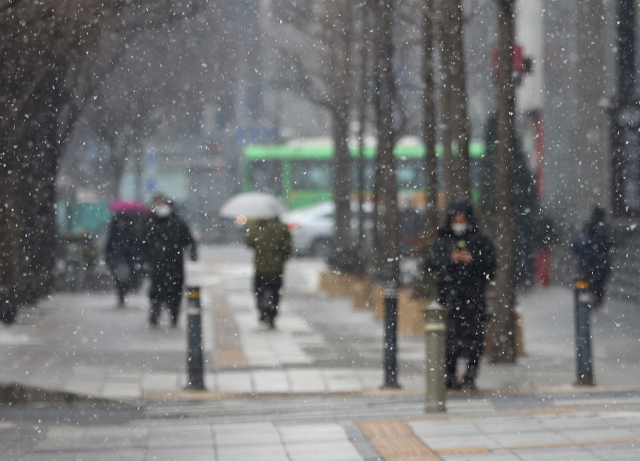 서울에 눈이 내린 12일 오후 서울 광화문 거리에서 시민들이 우산을 쓰고 이동하고 있다. 연합뉴스