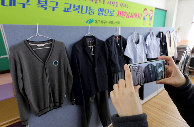 지난해 1월 31일 대구 북구자원봉사센터에서 관계자가 기증된 교복 사진을 휴대폰 앱에 등록하기 위해 사진을 촬영하고 있다. 북구청은 코로나19로 인해 비대면 방식으로 무료 교복 나눔행사를 진행해 북구 관내 교복 기증자와 수요자가