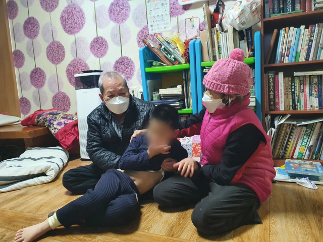 할아버지 정희창(가명·79) 씨와 할머니 신애영(가명·77) 씨가 발버둥 치는 손주 정선우(가명·7) 군을 붙들고 있다. 배주현 기자