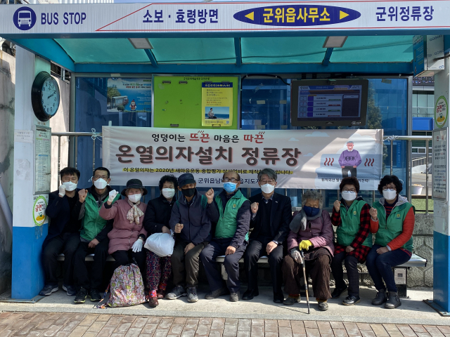 임병태(오른쪽 네 번째) 군위읍장과 주민들이 군위읍사무소 앞 버스정류장에 설치된 온열의자에 앉아 있다. 군위읍 제공