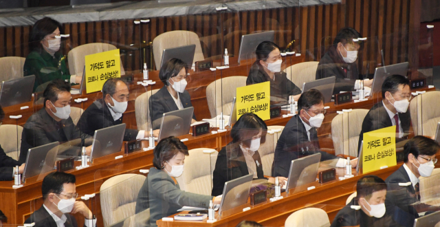 가덕도신공항 건설을 위한 특별법안(대안)이 26일 국회 본회의에 상정된 가운데 정의당 의원들이 자리에 반대 손팻말을 부착한 뒤 법안 찬반 투표를 하고 있다. 연합뉴스