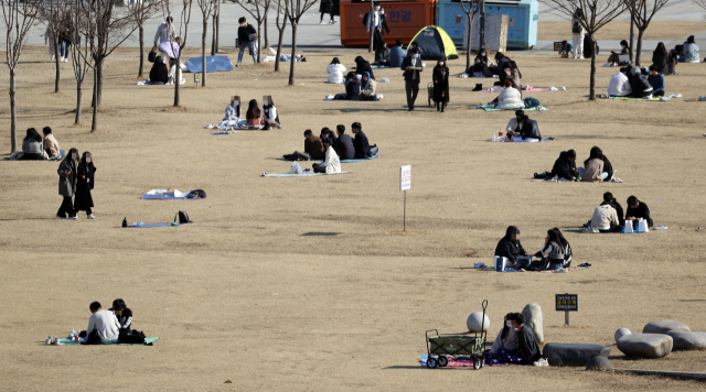 포근한 날씨가 이어지는 26일 오후 서울 영등포구 여의도한강공원에서 시민들이 잔디밭에 앉아 휴식을 취하고 있다. 연합뉴스