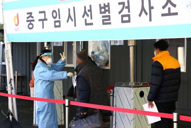 코로나19 신규 확진자 수가 415명을 기록한 27일 오전 서울역에 설치된 임시선별진료소에서 관계자가 검사 안내를 하고 있다. 연합뉴스