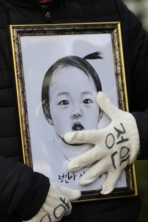 16개월 된 입양 딸 정인 양을 학대해 숨지게 한 혐의를 받는 양부모의 3차 공판이 열린 3일 오전 서울 양천구 남부지방법원 앞에서 한 시민이 정인이의 얼굴이 그려진 그림을 어루만지고 있다. 연합뉴스
