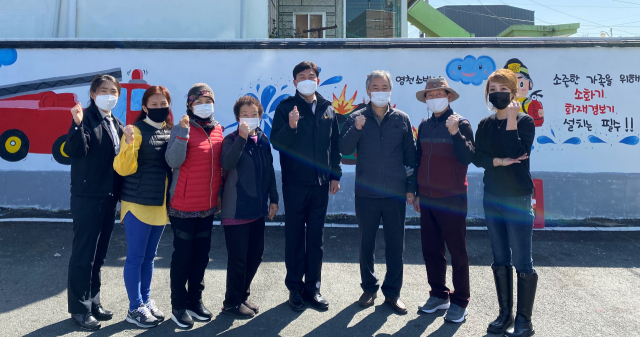 영천소방서에서 진행한 119안심골목 벽화마을 조성 행사에 참여한 자원봉사자와 마을주민들이 벽화그리기를 마친 후 기념촬영을 하고 있다. 영천소방서 제공