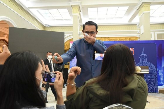 쁘라윳 짠오차 태국 총리가 9일(현지시간) 방콕에서 진행된 기자회견에서 난감한 질문을 피하기 위해 기자들을 향해 손소독제를 뿌리고 있다.