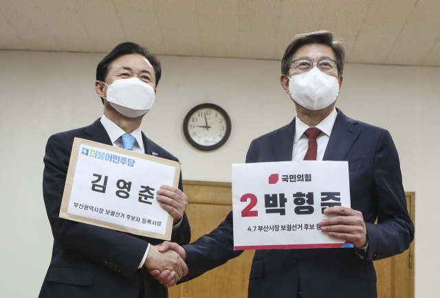 더불어민주당 김영춘(왼쪽)과 국민의힘 박형준 전 의원이 18일 오전 부산 연제구 부산시 선거관리 위원회에서 보궐선거 부산시장 후보 등록을 하며 만나 악수를 하고 있다. 연합뉴스