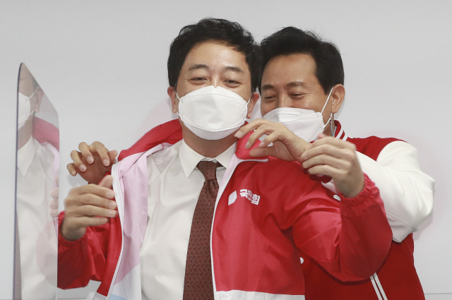 국민의힘 오세훈 서울시장 후보가 24일 오전 서울 여의도 중앙당사에서 열린 선거대책위원회 회의에서 금태섭 공동선거대책위원장에게 당 점퍼를 입혀주고 있다. 연합뉴스