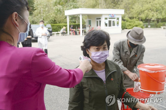 지난해 9월 북한 평양 시내의 식당 입구에서 한 여성이 체온을 재고 있다. 연합뉴스