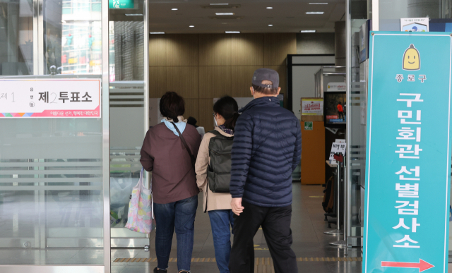 서울시장 보궐선거일인 7일 종로구 한 투표소에서 시민들이 투표하고 있다. 투표소 옆에는 부근 선별진료소 안내판이 놓여 있다. 이날 국내 신종 코로나바이러스 감염증(코로나19) 신규 확진자는 668명으로 치솟았다. 연합뉴스