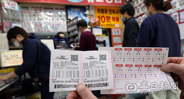 대구 시내 한 복권방에서 한 청년이 로또 번호를 하나의 패턴으로 모두 고정해 10장을 같은 번호로 구입한 로또복권과 용지를 보여주고 있다. 매일신문DB