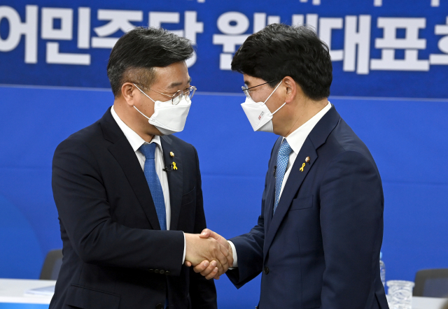 더불어민주당 원내대표 경선에 출마한 윤호중 의원(왼쪽)과 박완주 의원이 15일 서울 여의도 중앙당사에서 열린 합동토론회에서 악수하고 있다. 연합뉴스