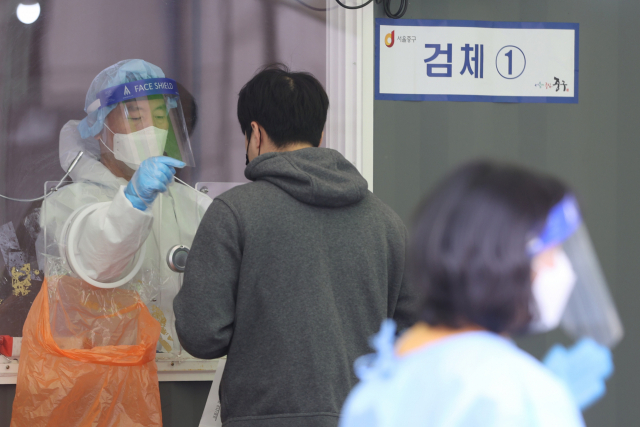 신종 코로나바이러스 감염증(코로나19) 신규 확진자가 658명 발생한 17일 오전 서울역광장에 마련된 임시선별진료소에서 의료진이 검체 채취를 하고 있다. 연합뉴스
