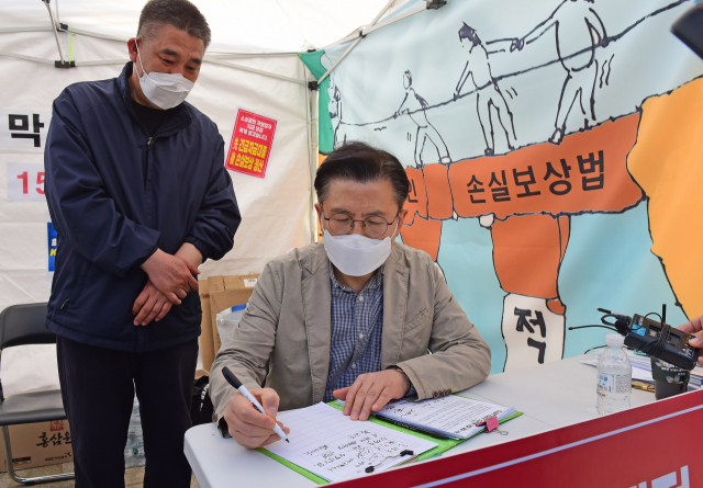 황교안 전 미래통합당 대표(오른쪽)가 지난 26일 서울 여의도 국회 본청 앞 국민의힘 최승재 의원과 소상공인들의 코로나19에 따른 손실보상 소급적용 입법 요구 천막농성장을 찾아 서명하고 있다. 연합뉴스