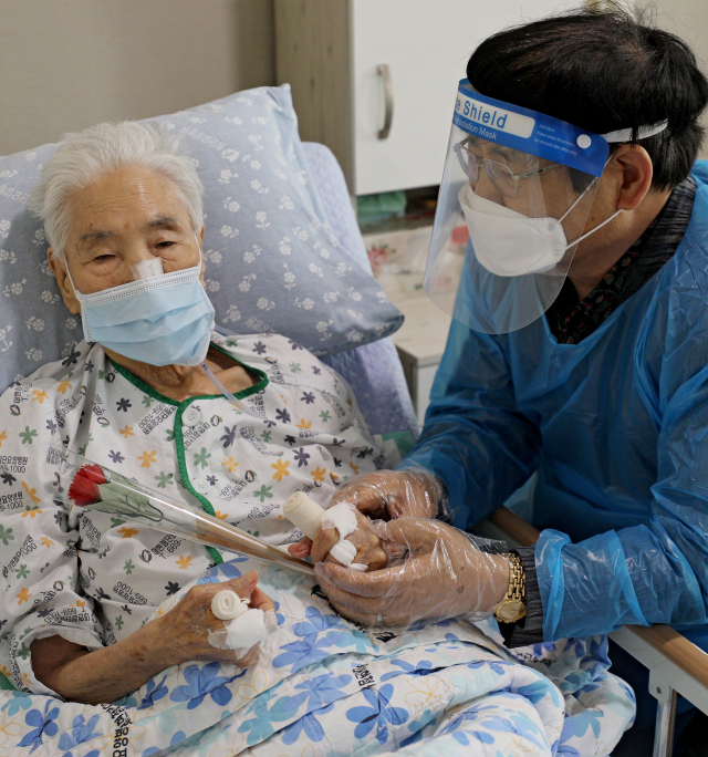 어버이날을 이틀 앞둔 6일 대구 북구 첨단요양병원에서 페이스쉴드와 방호복을 입고 면회 온 아들이 입원 중인 어머니의 손에 감사의 카네이션을 드리고 있다. 김영진 기자 kyjmaeil@imaeil.com