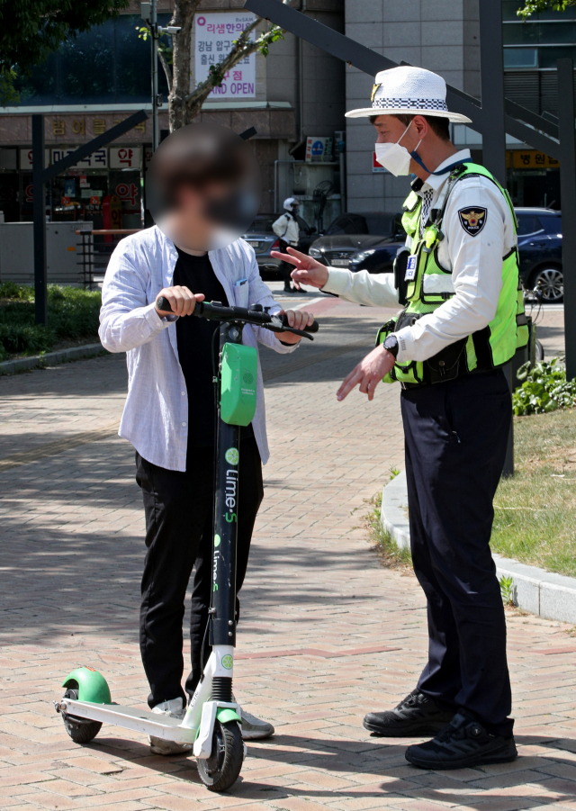 전동 킥보드와 전동 스쿠터 등 개인형 이동장치(PM)에 대한 안전 수칙이 강화된 개정 도로교통법이 시행된 13일 오후 대구 수성구 범어네거리에서 대구 수성경찰서 교통안전계 관계자가 헬멧을 착용하지 않은 전동 킥보드 이용자를 계도하고 있다. 김영진 기자 kyjmaeil@imaeil.com