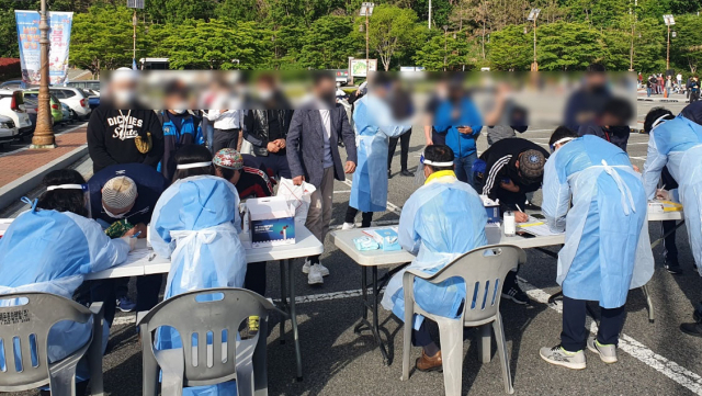 지난 13일 경남 김해시 가야테마파크 주차장에서 라마단 종료 행사인 이드 알 피트로 합동 예배에 앞서 방문자 등록을 하고 있다. 이 행사와 관련해 확진자 10명이 발생해 방역 당국에 비상이 걸렸다. 연합뉴스