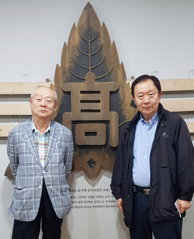 최근 대구에서 만난 이상무 경북중·고등학교 총동창회장(사진 왼쪽)이 경북고를 방문한 김능진 대구독립운동기념관 건립추진위원장과 모교의 모표를 사이에 두고 기념 촬영을 했다. (사진제공=경북중고등총동창회)