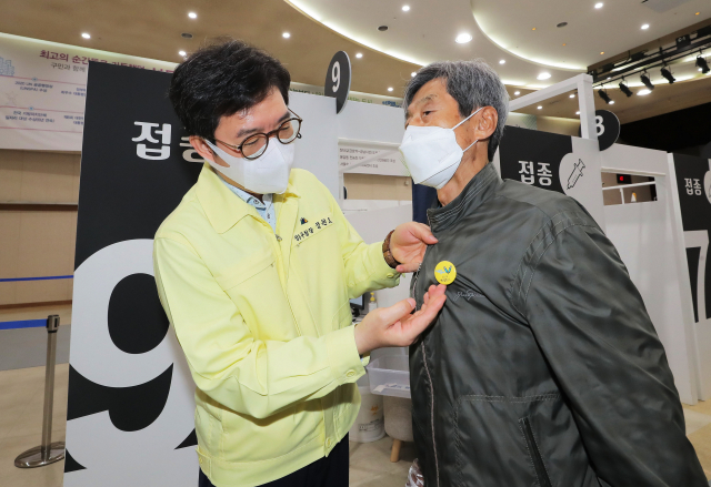 정원오 성동구청장이 22일 오전 서울 성동구청에 설치된 서울시 1호 코로나19 예방 접종 센터에서 2차 접종을 마친 한 어르신에게 안심배지를 달아드리고 있다. 연합뉴스