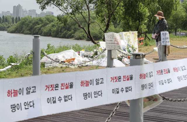 한강공원에서 실종됐다가 숨진 채 발견된 대학생 손정민 씨 사건에 대한 경찰의 수사가 진행 중인 25일 오전 손씨가 실종됐던 서울 서초구 반포 한강공원에서 시민이 추모 공간을 살펴보고 있다. 연합뉴스