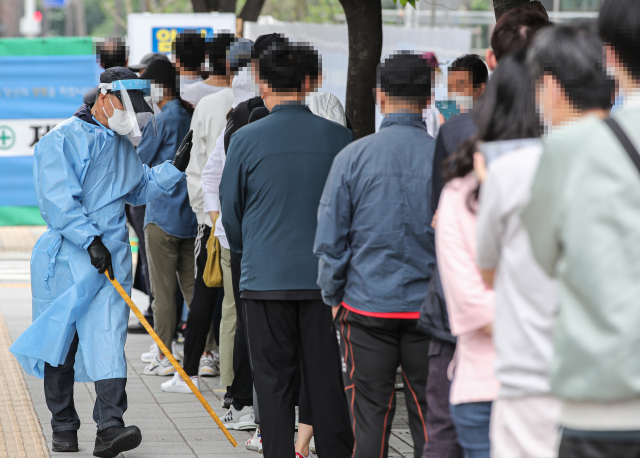 신종 코로나바이러스 감염증(코로나19) 신규 확진자가 연이틀 500명대를 기록한 29일 오전 서울시 송파구 보건소 선별진료소에서 관계자가 검사를 받기 위해 줄지어 서 있는 시민들에게 거리 두기를 안내하고 있다. 이날 보건 당국이 발표한 코로나19 신규확진자는 533명이다. 연합뉴스
