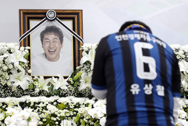 췌장암과 싸우다 세상을 떠난 유상철 전 인천 유나이티드 감독에 대한 추모가 이어지는 8일 오후 인천시 중구 인천축구전용경기장에 마련된 임시분향소에서 유 전 감독의 유니폼을 입은 팬이 조문하고 있다. 연합뉴스