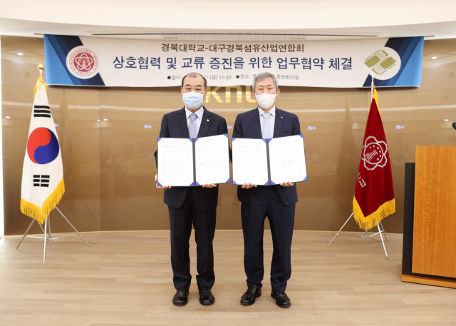 11일 경북대학교 중앙회의실에서 열린 업무협약식에서 조정문 대경섬산연 회장(오른쪽)이 홍원화 경북대 총장과 김념촬영을 하고 있다. 대구경북섬유산업연합회 제공