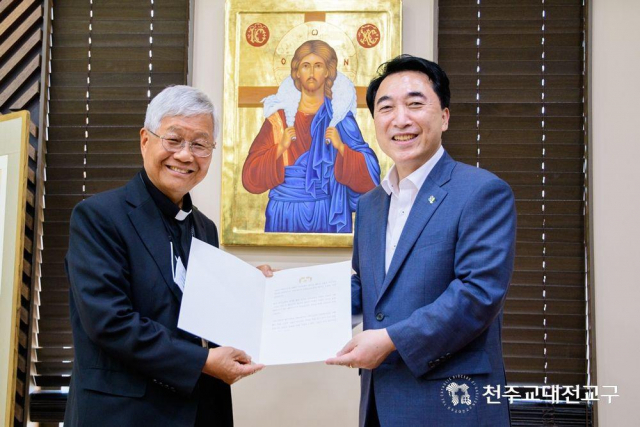 박수현 청와대 국민소통수석(오른쪽)이 12일 천주교 세종시 대구교구청에서 한국인 최초로 교황청 장관에 임명된 유흥식 대주교를 만나 문재인 대통령의 축전을 전달하고 있다. 연합뉴스
