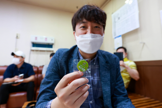 민방위 대원인 국민의힘 이준석 대표가 15일 오전 서울 노원구 한 병원에서 코로나19 얀센 백신을 접종했다. 접종을 마치고 이 대표가 배지를 들어보이고 있다. 연합뉴스