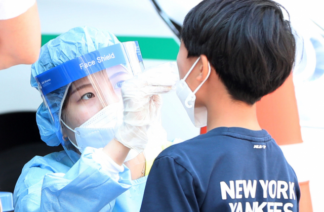 21일 강원 춘천시보건소에 마련된 선별진료소에서 어린이가 신종 코로나바이러스 감염증(코로나19) 검사를 받고 있다. 이날 춘천의 한 초등학교에서 학생 1명이 코로나19 확진을 받아 해당 학교의 학생 등교가 임시 중단됐다. 연합뉴스