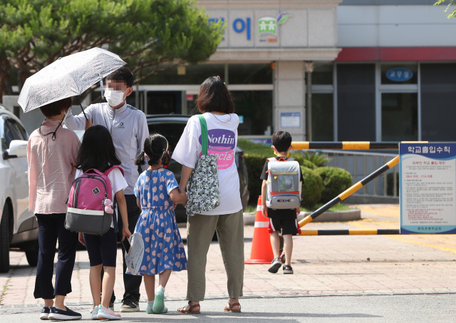 22일 강원 춘천시의 한 초등학교에에 마련된 선별진료소에서 어린이들이 부모님과 함께 신종 코로나바이러스 감염증(코로나19) 검사를 받으러 발걸음을 옮기고 있다. 해당 학교에서는 이날 학생과 교사 등 9명이 코로나19 확진을 받아 등교가 임시 중단됐다. 연합뉴스