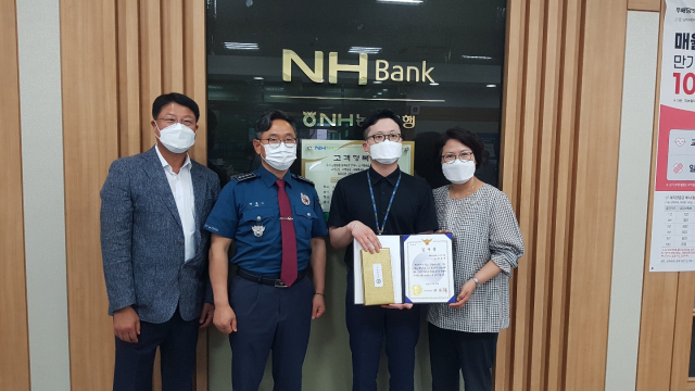 안문기 상주경찰서장이 보이스 피싱 피해를 사전에 막은 상주 농협 직원에게 감사패를 수여한 뒤 기념촬영을 하고 있다. 상주경찰서 제공