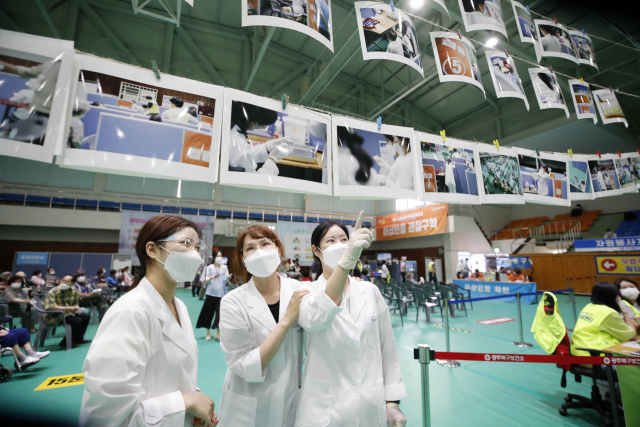 28일 오전 광주 북구 백신 예방접종센터에서 보건소 직원들이 국내 백신 접종이 시작된 지 123일을 맞아 북구청 홍보팀이 오랜 기간 촬영한 백신 접종 관련 사진을 받아 전시하고 있다. 연합뉴스